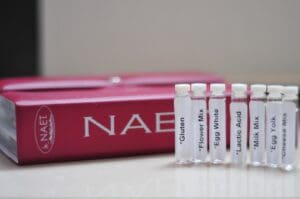 A box of naes with four test tubes in front.