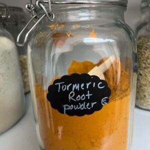 Jar of turmeric root powder with scoop.