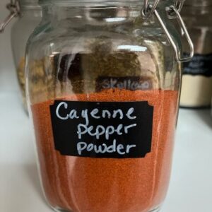 Jar of cayenne pepper powder on shelf.
