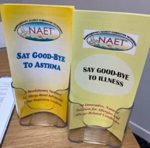 Two yellow NAET brochures in a plastic holder.